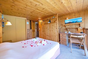 Ein Schlafzimmer einer Holzhütte mit einem Bett, einem Schreibtisch und einem Stuhl.