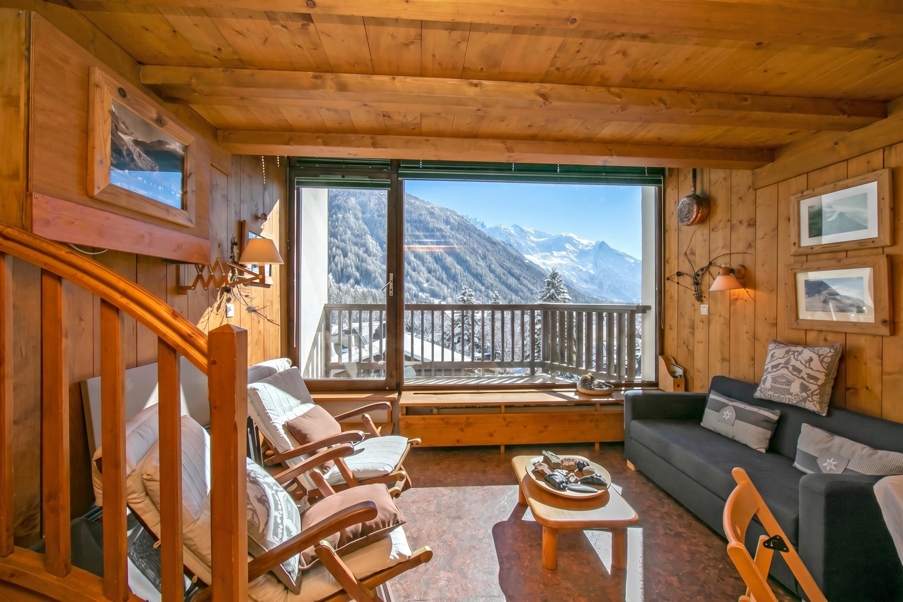 Eine Holzhütte mit einem Balkon, ausgestattet mit einer Couch, Stühlen und einem Tisch.