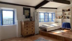 Ein Schlafzimmer mit einem Bett, einem Schminktisch und zwei Fenstern mit blauen Rahmen.