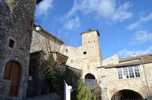 Un bâtiment en pierre doté d’une tour, de portes en arc de cercle et surplombé d’un ciel d’un bleu éclatant.