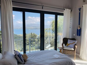 Relax in this serene bedroom with a large bed, sliding glass door to a balcony, and scenic lake views.