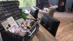 Ein gemütliches Interieur mit einem Korbwäscher voller Snacks, einem Tisch mit Tellern und Besteck, einer Couch und einem Kaminofen.
