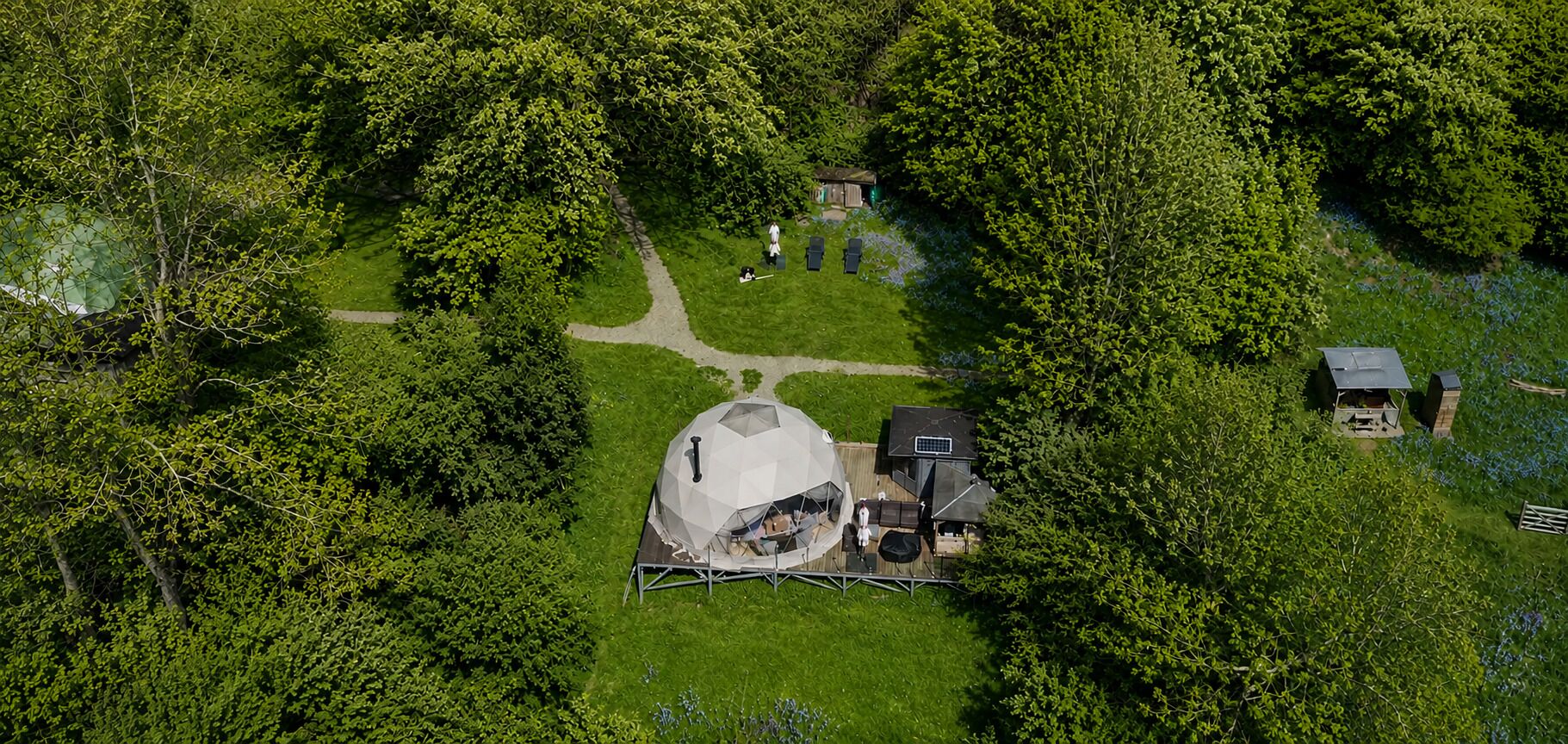 A large, dome-shaped structure with a covered seating area, surrounded by a well-maintained lawn and trees.