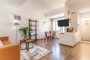 Een woonkamer met een bank, een salontafel, een plant en een boekenkast.