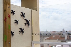 A balcony with decorative bird figures, a wooden post, and a glass railing.