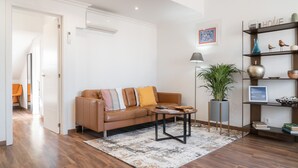 A modern living room with a leather sofa, a coffee table, a floor lamp, and a bookshelf.