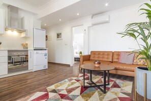 Una sala moderna con sofá, mesa de centro y una cocina equipada.