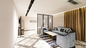 Una sala de estar moderna con un sofá, un sillón y una mesa de centro, con suelo de estampado geométrico y una partición decorativa.