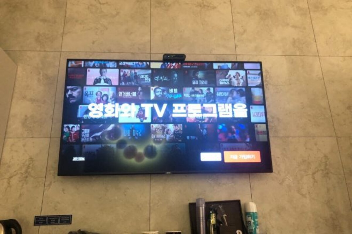 Un televisor montado en la pared mostrando diversos programas de televisión.