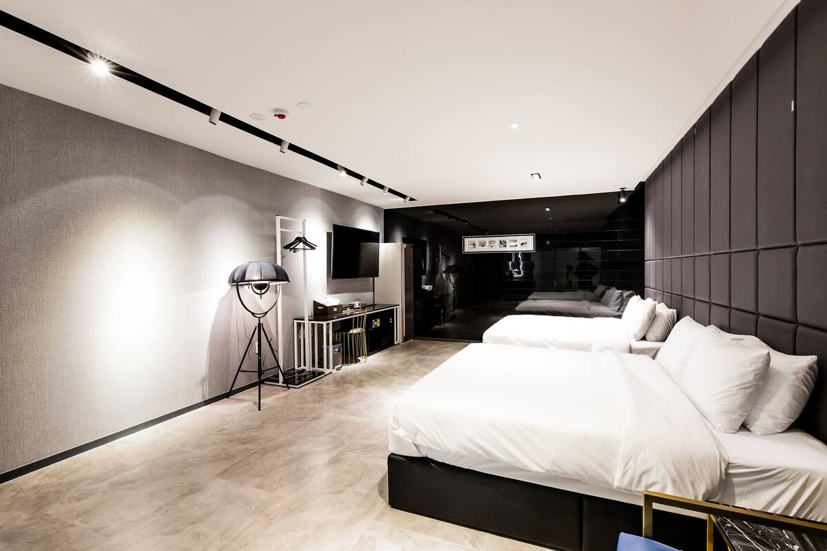 Ein modernes Hotelzimmer mit zwei Betten, einem Schreibtisch und einem Kleiderschrank.