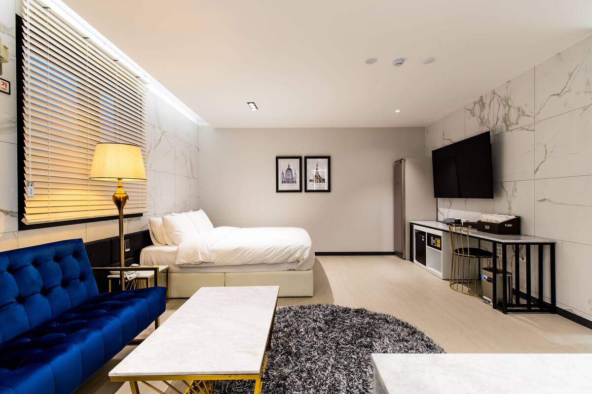 Ein modernes Hotelzimmer mit Bett, Sofa, Fernseher und Schreibtisch.