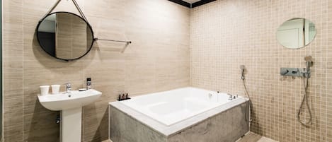 Un baño moderno con una bañera independiente, un lavabo sobre pedestal y un espejo redondo.
