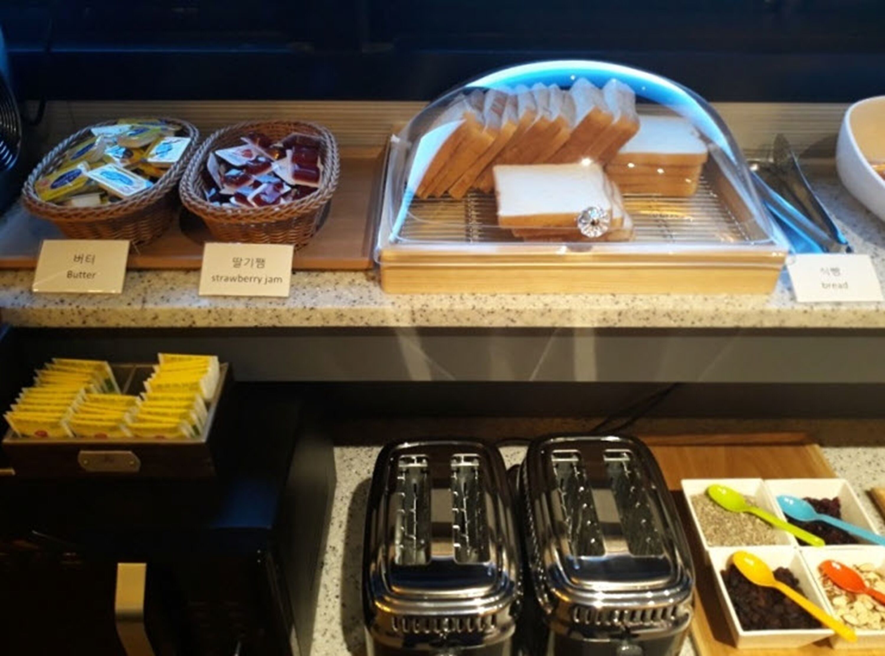 A breakfast buffet with labeled items including butter, strawberry jam, and bread.