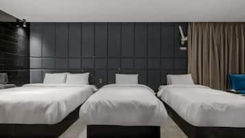 A modern hotel room with three beds aligned in a row, dark paneling on the walls, and a large window with curtains.