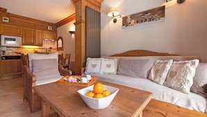 A cozy living room with a wooden table, a bowl of oranges, and a sofa with heart-shaped pillows. - Le Cristal Lognan7 Mountain View, Argentière (Chamonix), France (Argentière (Chamonix))