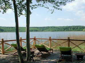 Une terrasse en bois avec des chaises et vue sur un lac.