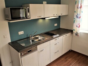 Una kitchenette compacta con microondas, pileta y horno integrado.