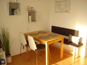 Un coin repas avec une table en bois, quatre chaises, un banc et une plante en pot.