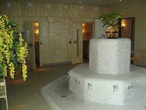 Un hall d’hôtel doté d’une fontaine centrale, de murs recouverts de panneaux en bois et d’une plante en pot.