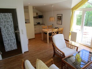 Un coin repas avec une table et des chaises, une cuisine en arrière-plan et une fenêtre avec des rideaux.