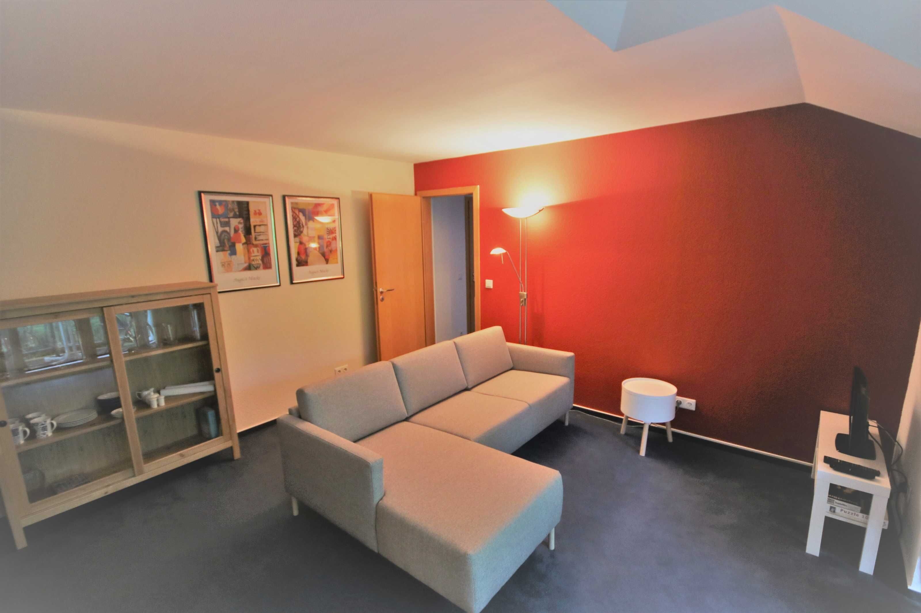 Un salon comprenant un canapé, un meuble avec des portes en verre, une lampe et un téléviseur posé sur un meuble.