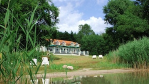 Hotel amb vistes al llac, un edifici gran, zona d'estar a l'aire lliure i un estany.
