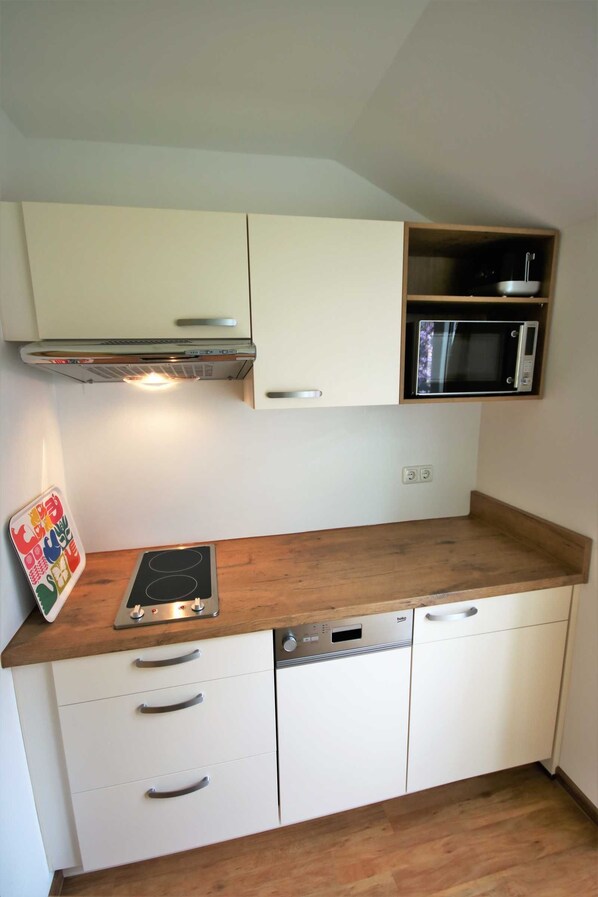 A compact kitchen with a microwave, stove, and dishwasher.