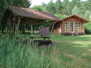 Eine rustikale Holzhütte mit Veranda und überdachter Außenbereich mit Sitzgelegenheit.