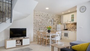 A modern living room with a TV, dining table, chairs, and a sofa. - Villa Petit **** villa in Brela, private pool (Brela)