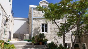 A stone building with a small staircase leading to a door, surrounded by potted plants and a tree. - Villa Petit **** villa in Brela, private pool (Brela)