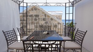 A covered outdoor dining area with a stone wall and a view of the sea. - Villa Petit **** villa in Brela, private pool (Brela)