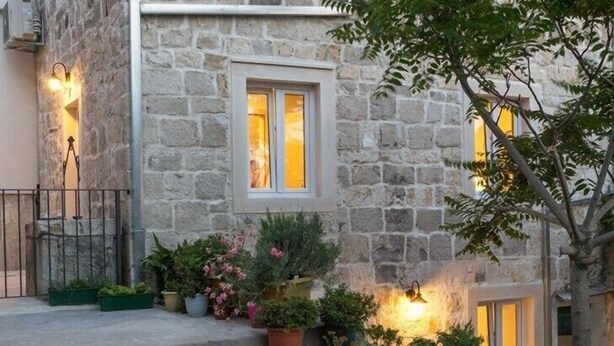 A stone building with a staircase leading to the entrance, surrounded by potted plants and a tree. - Villa Petit **** villa in Brela, private pool (Brela)