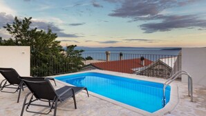A rooftop pool with a view of the sea and a red-roofed building in the background. - Villa Petit **** villa in Brela, private pool (Brela)