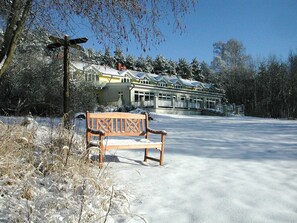 En bænk i et snækkedækket udendørsområde med en bygning i baggrunden.