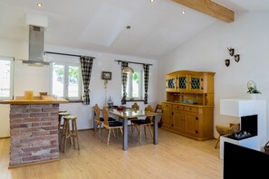 A spacious kitchen with a brick island, wooden chairs, and a wooden cabinet.