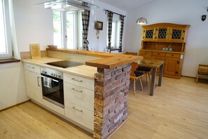 A kitchen with a brick island, wooden cabinets, and a dining area with a table and chairs.