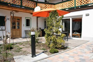 A courtyard with a wooden deck, a small tree, and a black bollard.