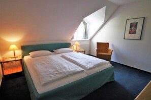 A hotel room with a bed, two bedside lamps, a chair, a window, and a framed picture on the wall. - KIWI Apartment 8 - KIWI Apartments on Lake Dreier (Alt Schwerin)