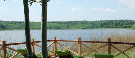 Una terraza de madera con sillas y vistas a un lago.