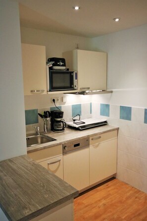 A compact kitchen with a microwave, coffee maker, and a small countertop. - KIWI Apartment 8 - KIWI Apartments on Lake Dreier (Alt Schwerin)