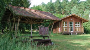 A rustic wooden cabin with a porch and a covered outdoor seating area.