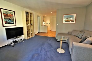 A living room with a TV, sofa, and a glass coffee table. - KIWI Apartment 8 - KIWI Apartments on Lake Dreier (Alt Schwerin)