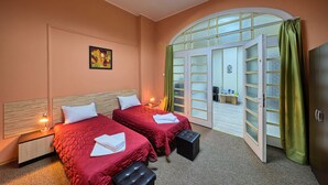 Habitación de hotel con dos camas, un ventanal grande de arco y vistas al exterior.