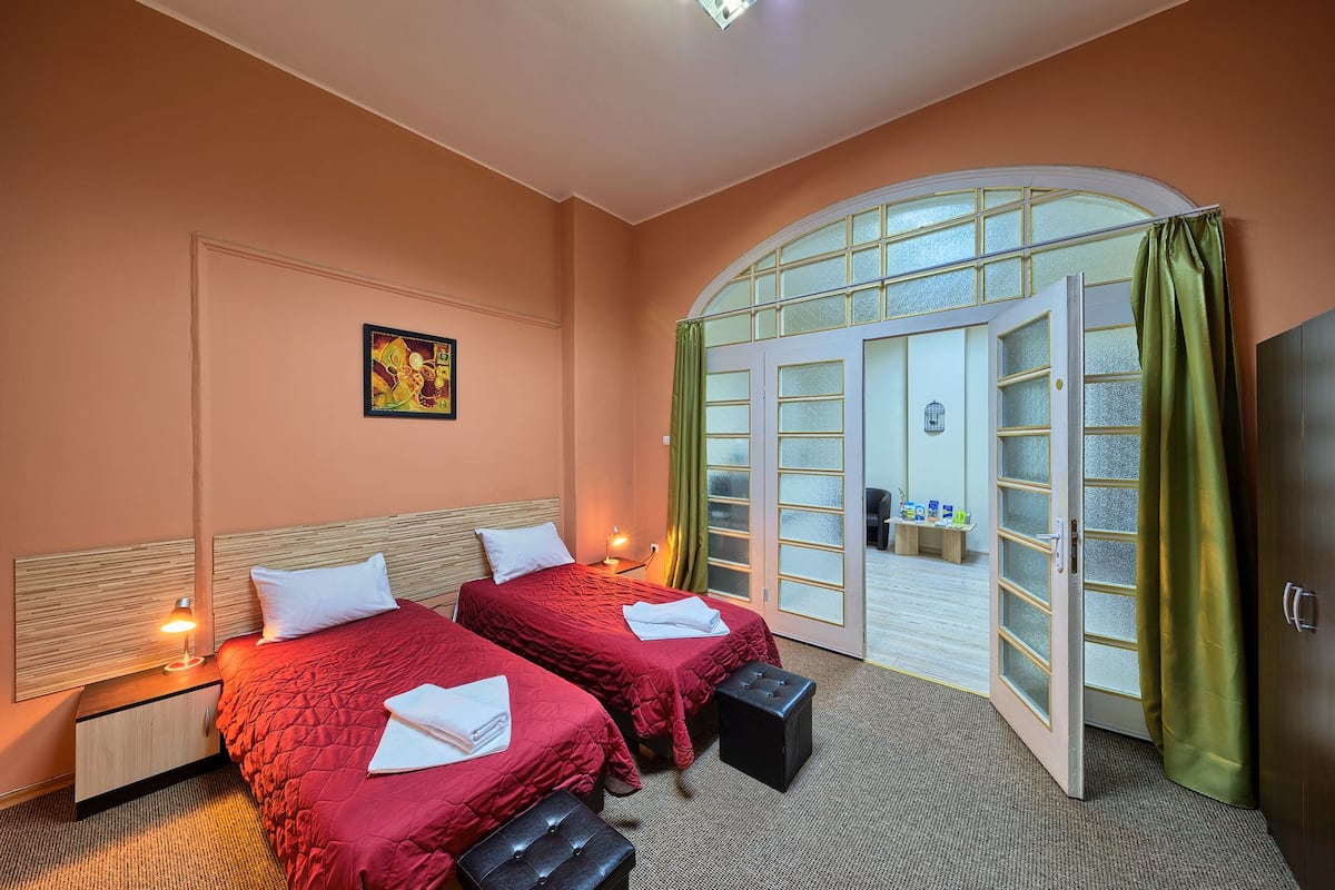 A hotel room with two beds, a large arched window, and a view of the outside.