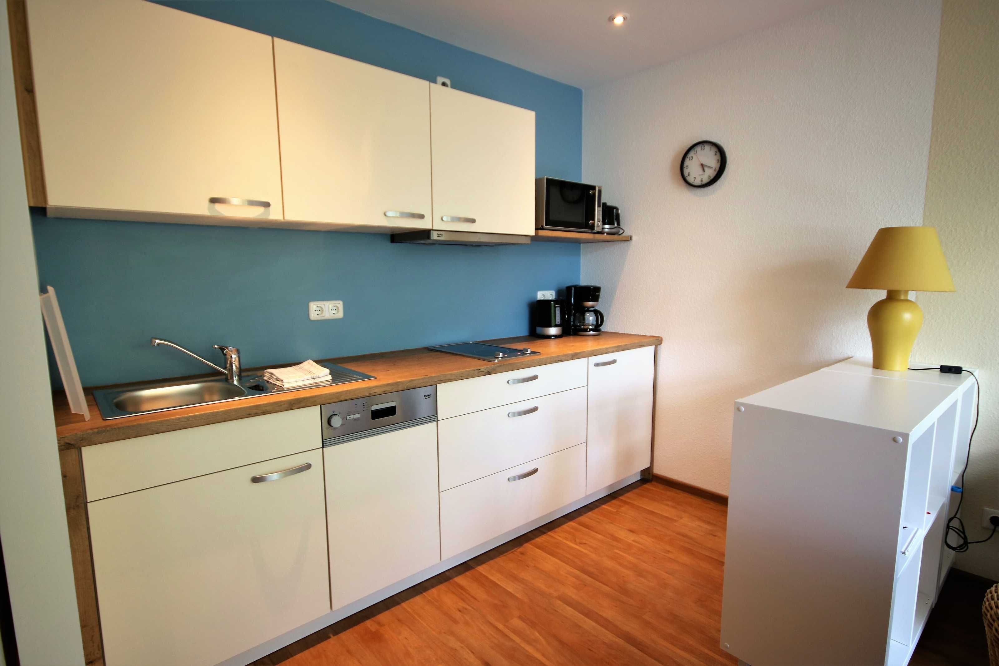 A compact kitchen with white cabinets, a microwave, a coffee maker, and a small refrigerator.