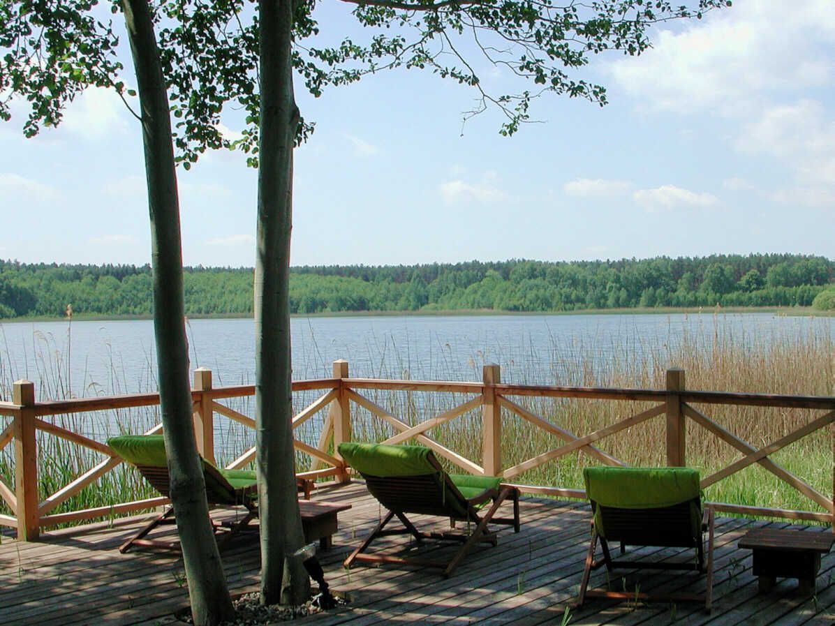 Une terrasse en bois avec des chaises et vue sur un lac.