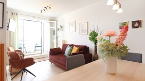 A modern living room with a sofa, chairs, a dining table, and a vase of flowers. - Haffblick Whg. Ha31, Germany (Ostseebad Boltenhagen)