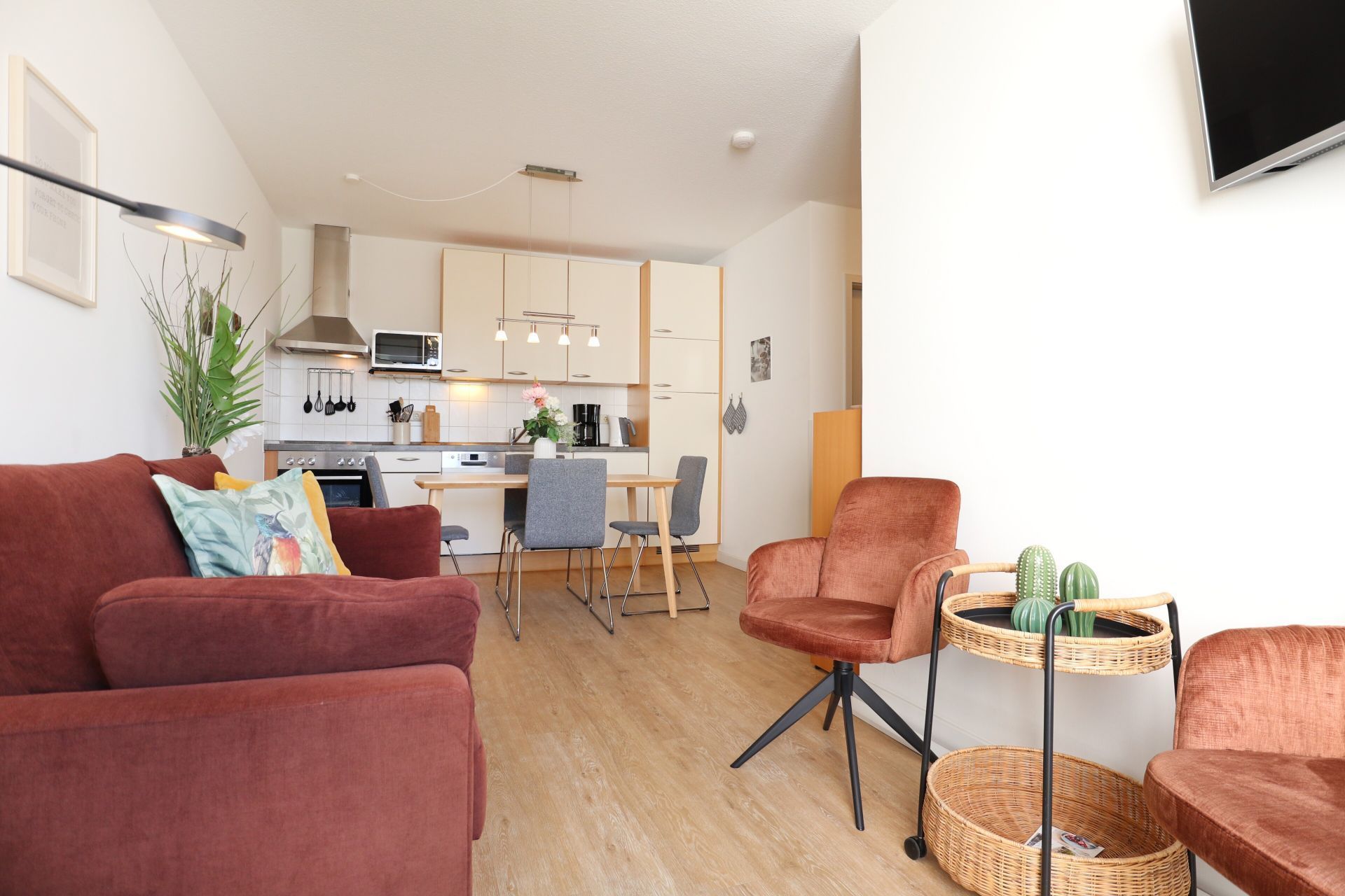 Una sala moderna con un sofá, un sillón y una pequeña mesita con un cactus.