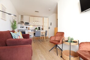 A modern living room with a sofa, armchair, and a small side table with a cactus. - Haffblick Whg. Ha31, Germany (Ostseebad Boltenhagen)