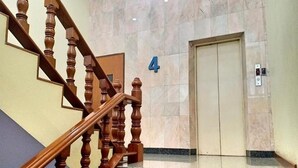 A wooden staircase with a marble wall and a door marked with the number 4. - Hua Lin Inn (Chiang Mai)